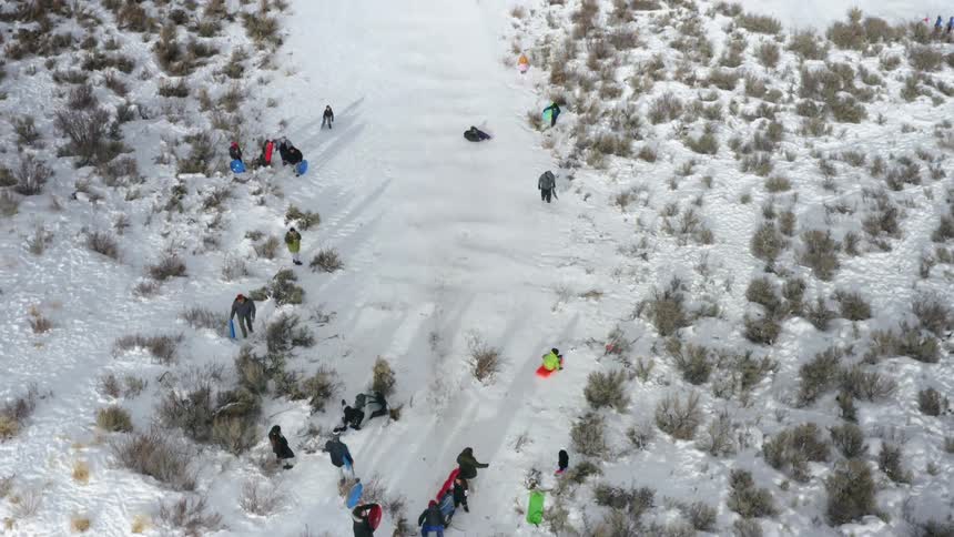 People slide down a snow covered slope using tubes toboggans and sleds