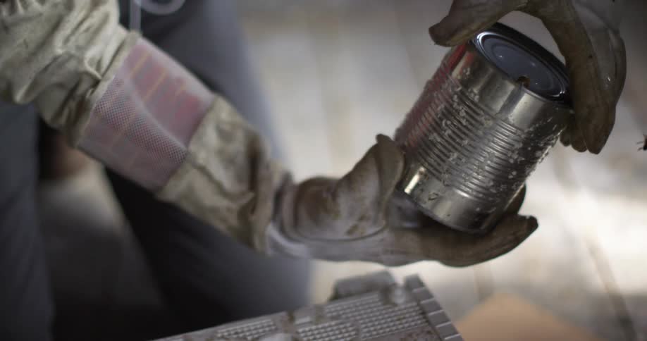 Beekeeper removing a tin can used to cover an indoors bee hive