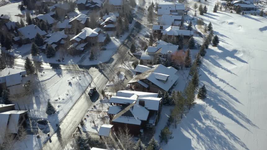 A truck travels down a road through a snowy town during the day