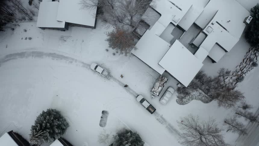 Two people walking away from a parked car outdoors in the snow in front of a house at daytime
