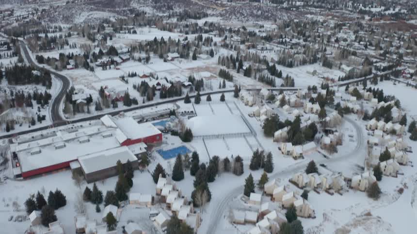 The rooftops of buildings in a small snow covered town with mountains on the horizon