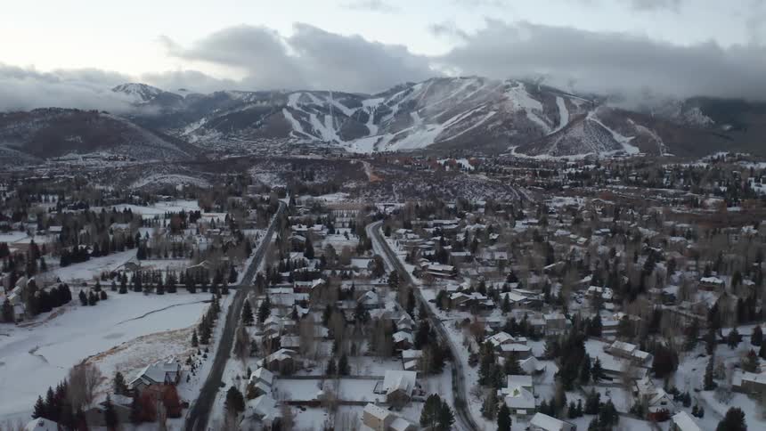 Snow covered homes and a town at the base of mountains with ski trails