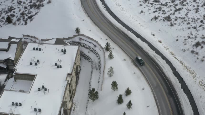 A window run leading passed snow covered buildings and hills in the countryside during the day