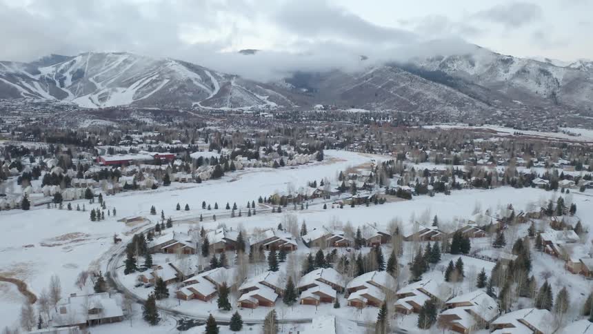 Snow covered community under a cloudy sky with mountains in the distance