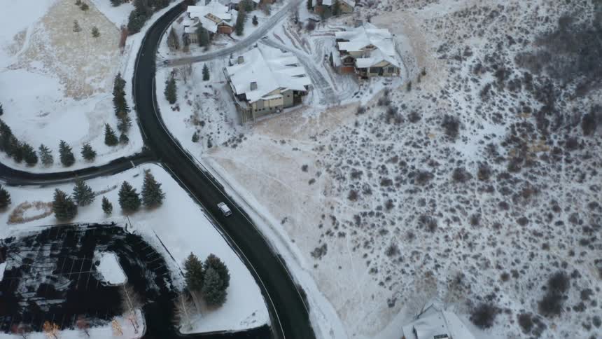 A town with houses a road and trees covered in snow