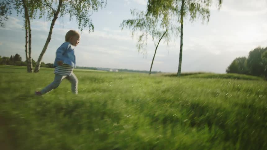 Little girl running into his father arms on a grass field