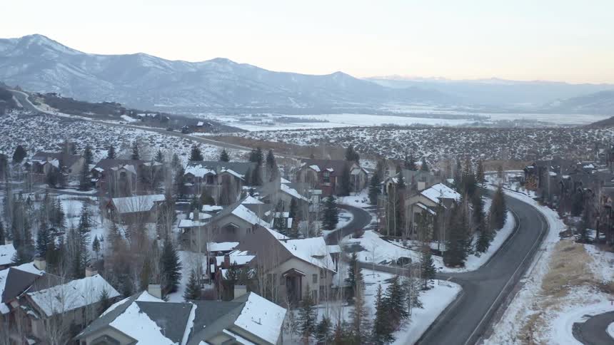 Aerial view of houses in a small town covered in white snow at winter near a lake in the mountains