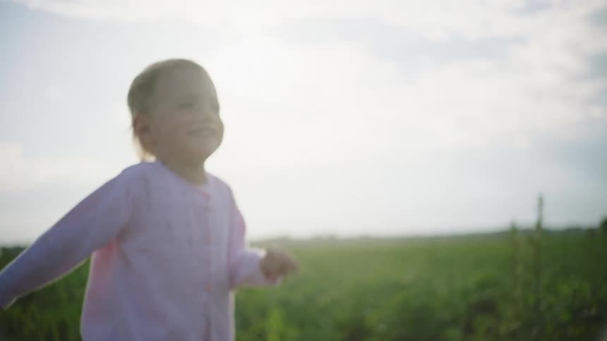 Little girl playfully running on a dirt road through a grass field