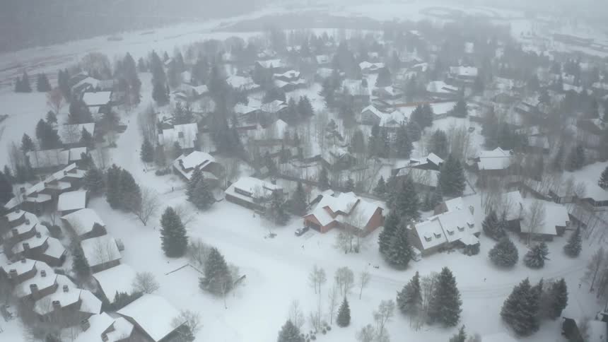 A small town covered in snow and mist on a winter day