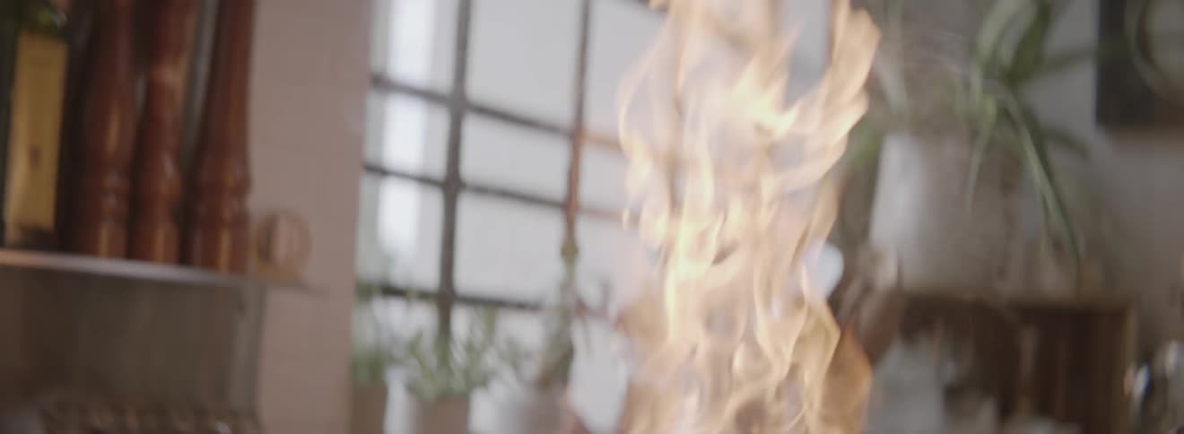 A person cooking with a pan as it goes on fire