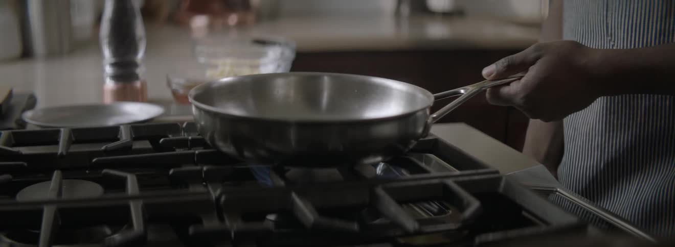 A person watches a pan on the stove