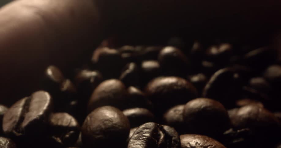 Brown roasted coffee beans moving around in a persons hand
