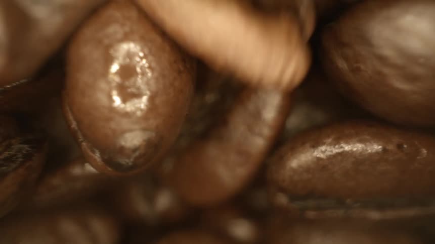 Brown roasted coffee beans piled up around the moving camera