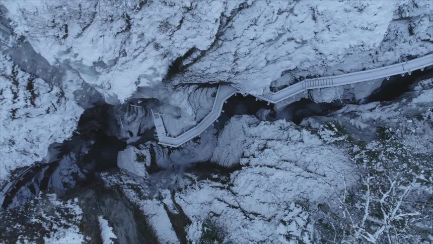 A winding snow covered walkway ascending the wall of a canyon on a winter day