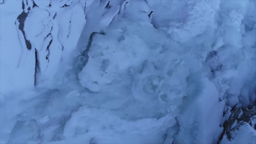 A stream of water flowing over snow and ice in nature