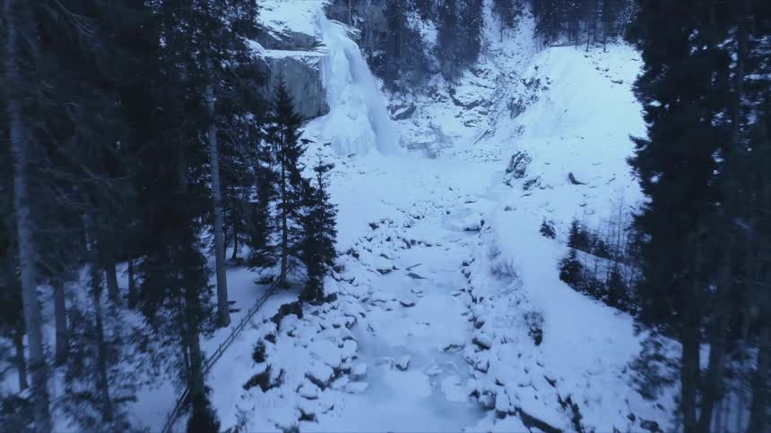 Aerial view of a waterfall flowing over the rock cliff of a mountain at winter
