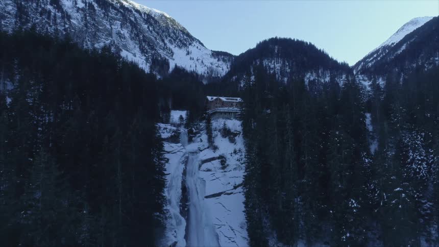 A waterfall flowing over a cliff in snowy mountains on a winter morning