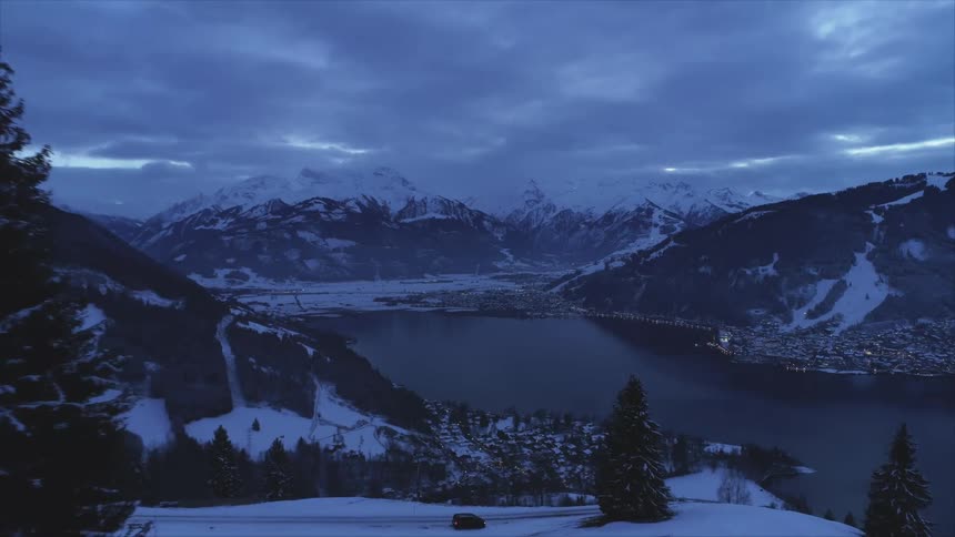 An aerial view of a lake in a mountain range with a neighborhood nestled on the shore