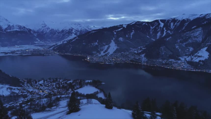 A town along the banks of a river in a snowy mountain valley on a cloudy evening