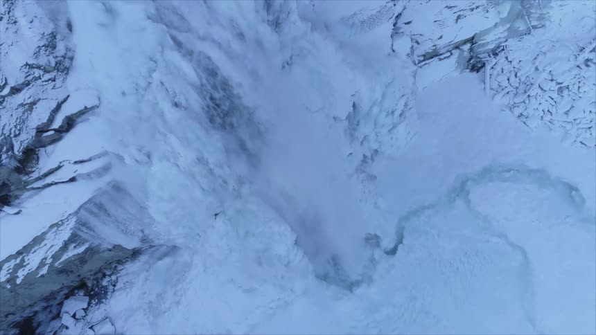 Waterfal pouring ver the frozen cliff of a snow covered mountain