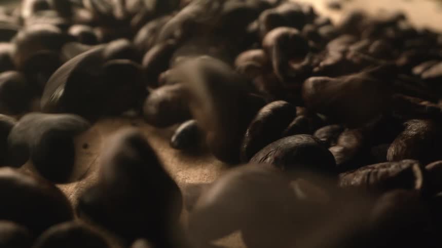 Brown roasted coffee beans falling onto wooden table