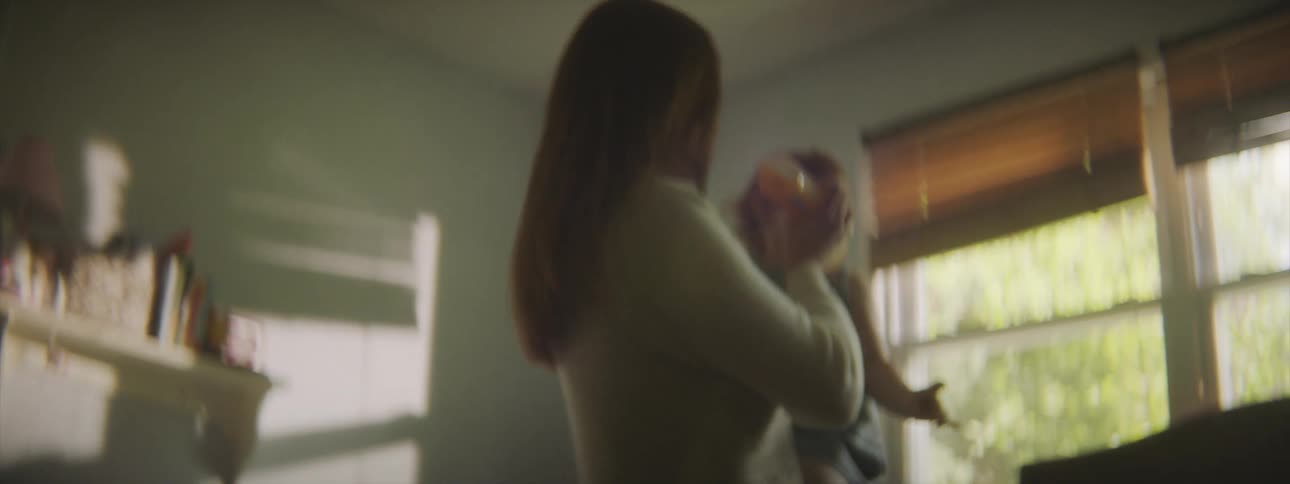 A woman feeds her baby a bottle before setting her in her crib