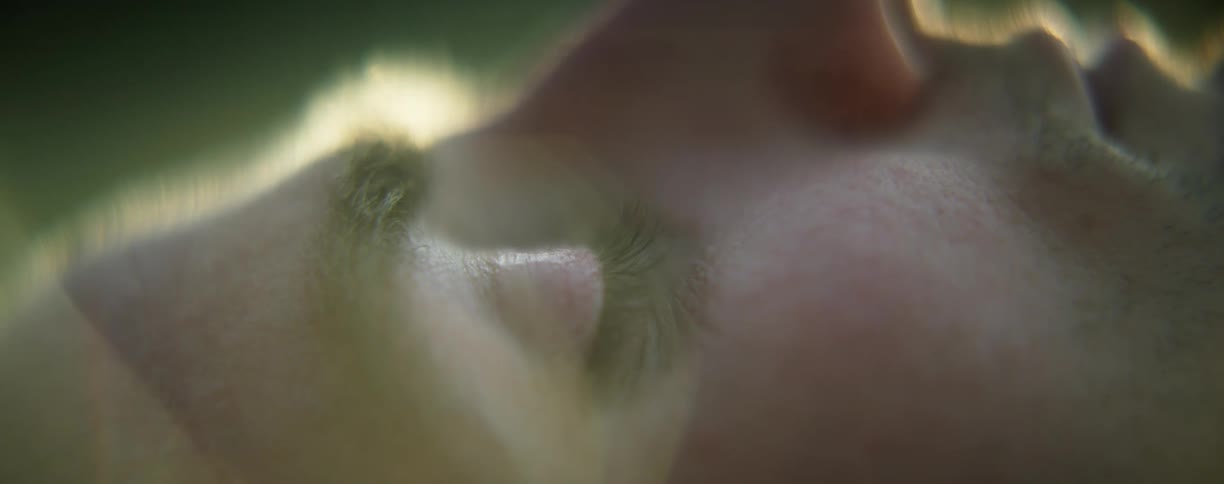 A man rests on his back with his eyes closed outdoors during the day