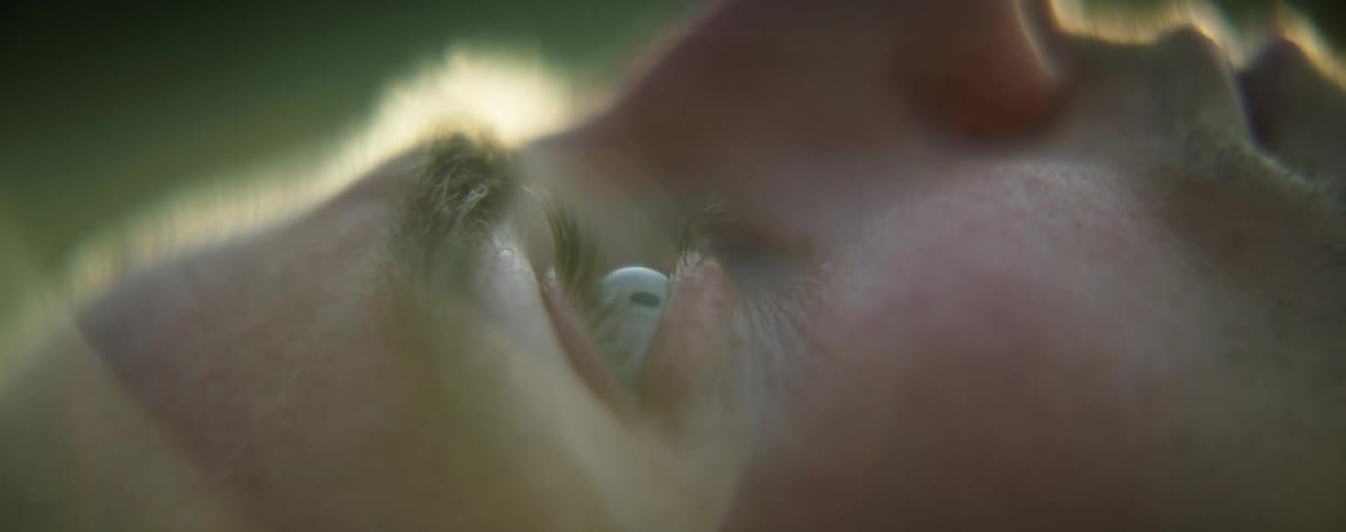 A person laying down and opening their eyes