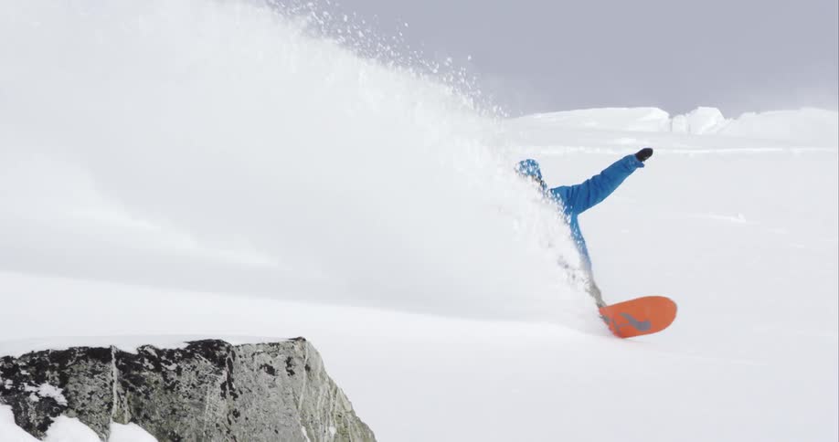 A snowboarder spraying snow as he weaves down the mountain