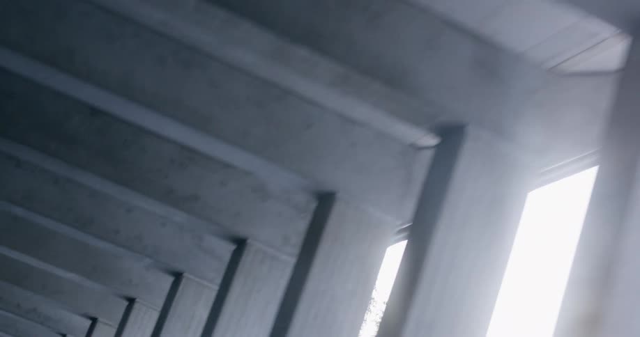A concrete overpass structure with openings revealing daylight during the day