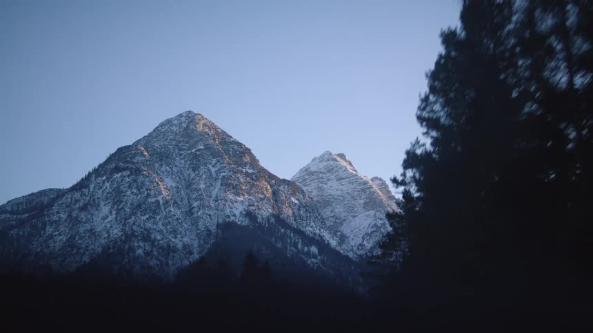 Traveling towards rocky mountain peaks past evergreen trees