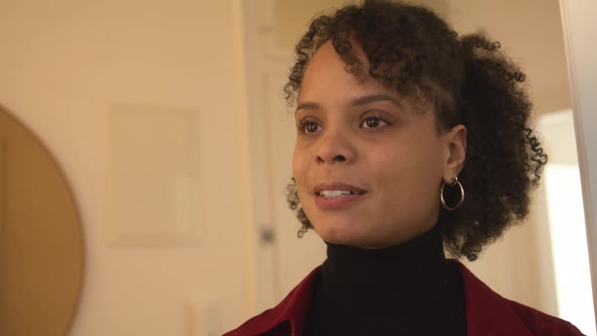 Close up of a tense or nervous young woman standing in the hallway of a house