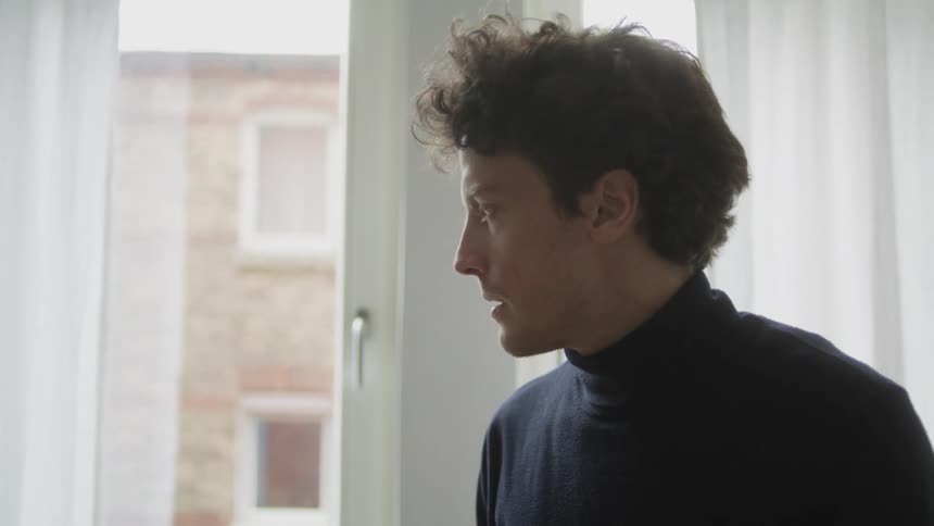 Fearful and nervous man tensely touches his hair standing in a room at home