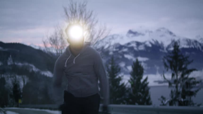 A man is jogging outdoors in winter at dusk