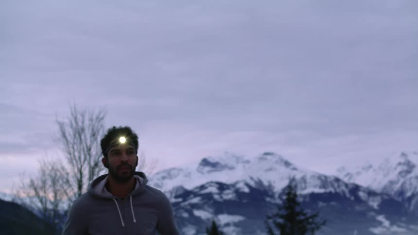 A man jogs in place above a lake in front of a mountain range
