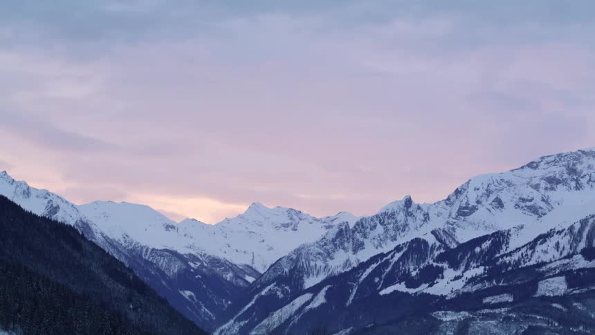 A view of mountains with snow on them at sunset