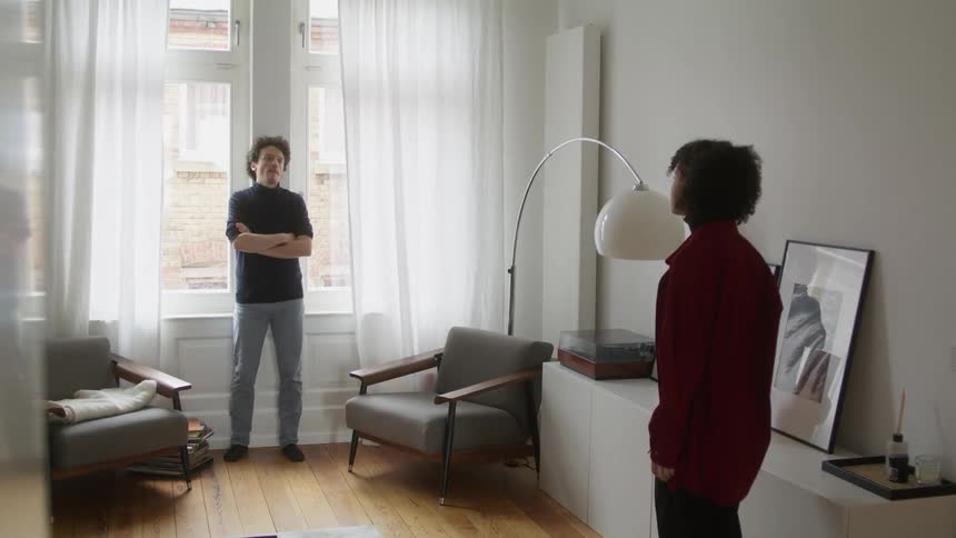 A man and woman are arguing in the living room of a home