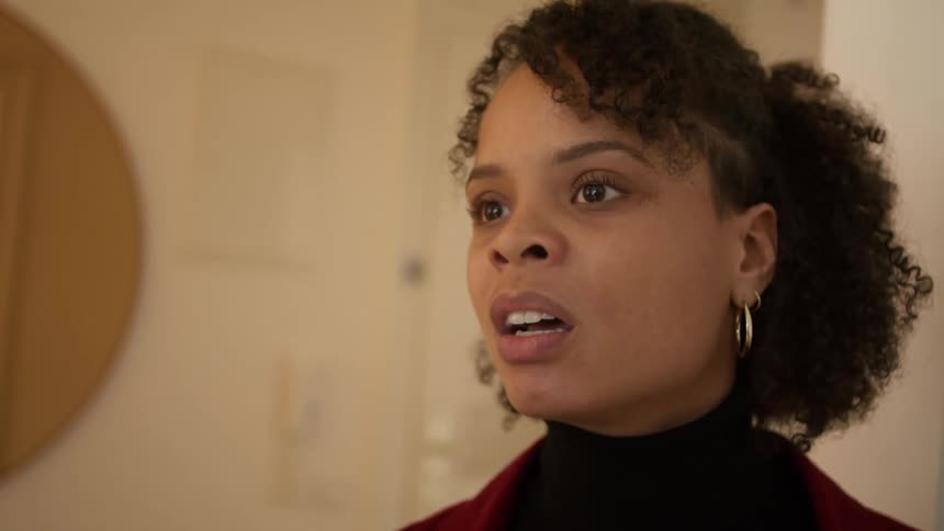 A woman standing in a room arguing with a wall and a door in the background