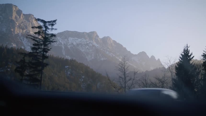 Vehicles driving on a road near the snow covered mountain range at morning