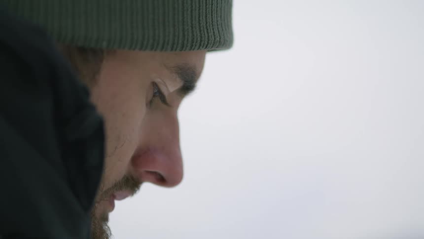 A person is standing outdoors and wearing a hat