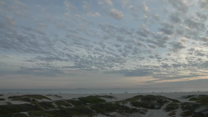 People are standing near the water of a beach in the distance