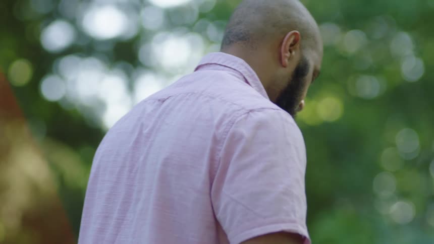 A man grilling outside near trees on a summer day