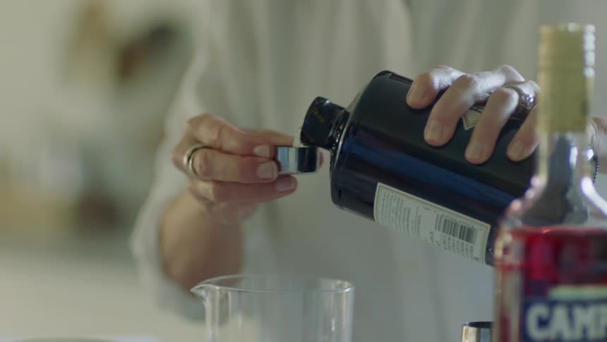 A woman mixing a drink in a glass at home