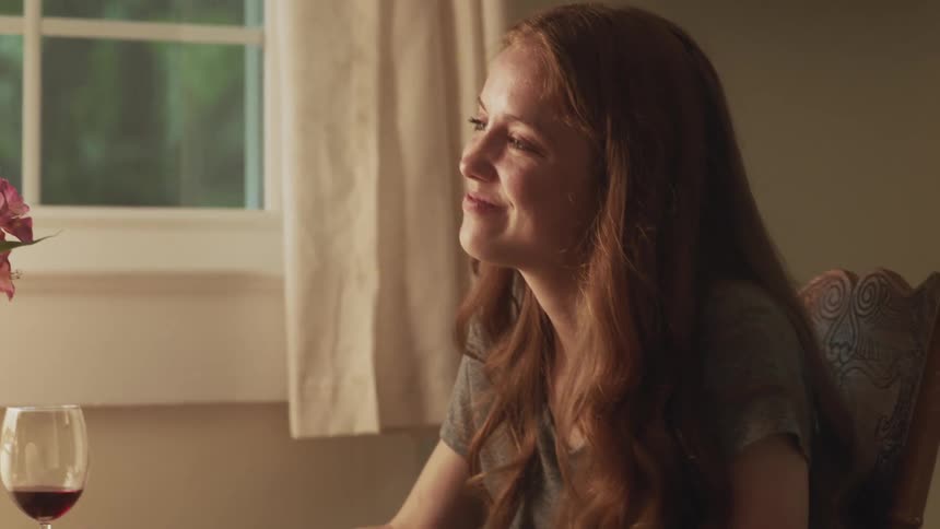 Young woman sitting on a chair on a date talking to someone at home
