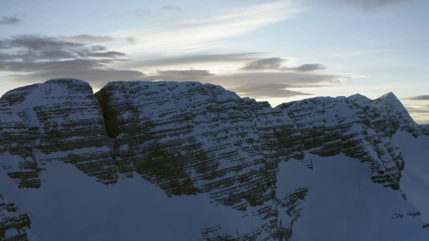Aerial view of snow covered mountains at dusk is displayed