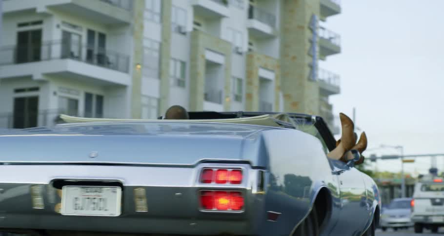 Texans driving down a city street in a blue convertible
