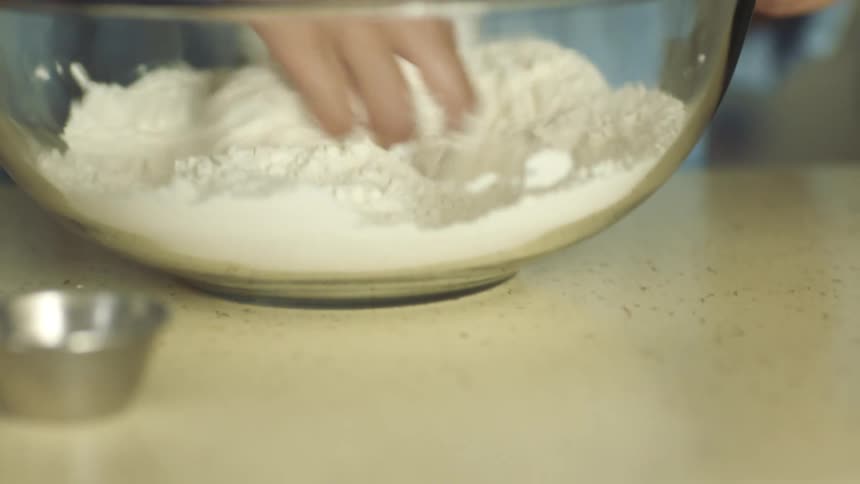 Young woman mixing flour in a mixing bowl over the kitchen counter top at home