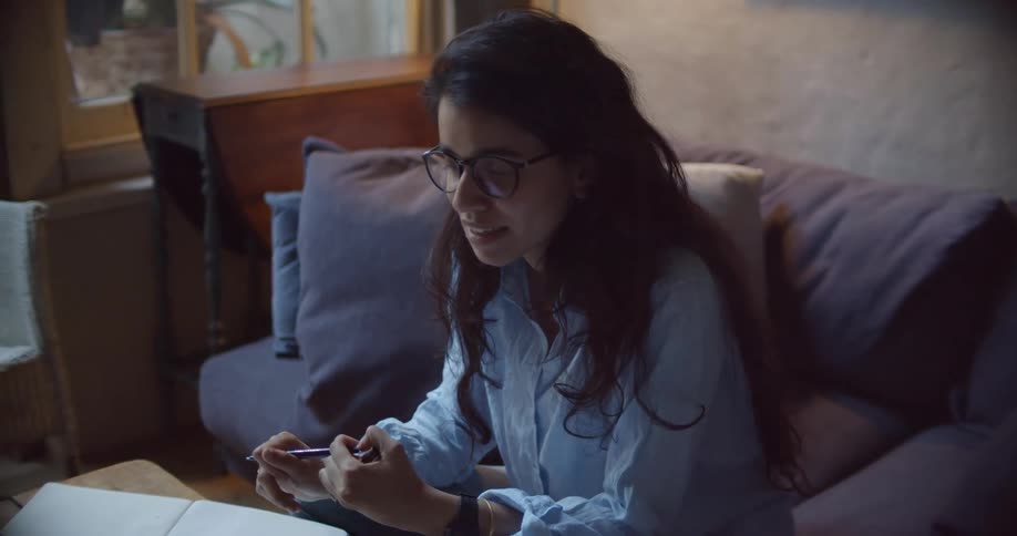 Woman laughs while sitting in living room and conversing through laptop video call