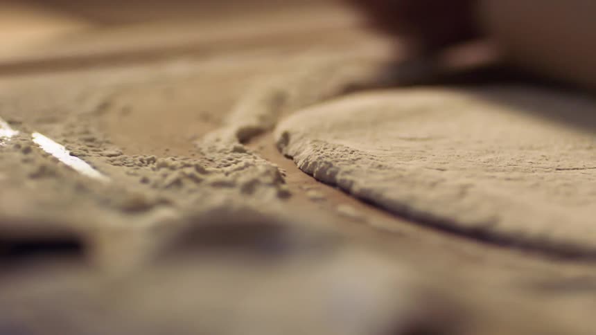 Rolling out dough on a cutting board with a rolling pin