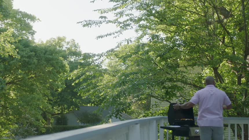 A man cooking barbeque on the porch at home